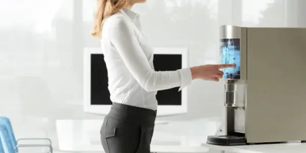Vrouw die water uit drinkwaterkoeler pakt